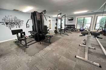 A gym with weights and other equipment in a building with windows